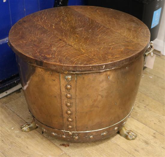 A copper two handled cylindrical log cauldron, on lions feet, with oak cover, diameter 1ft 10in.